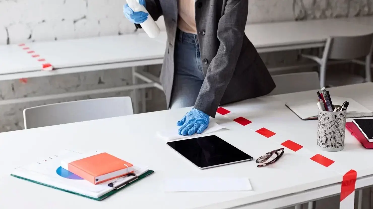 Detective in gloves examining a tablet and documents at a taped-off crime scene desk